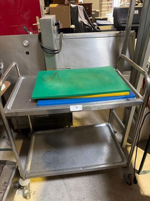 une table en métal sur laquelle est posée une planche à découper verte