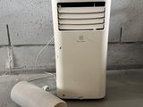 un climatiseur blanc posé par terre à côté d'un rouleau de papier toilette