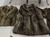 several coats of fur are lined up on the floor in a store
