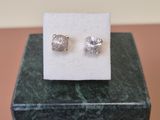 a pair of earrings sitting on top of a marble block