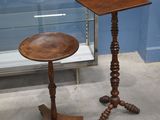 une petite table avec un plateau en bois et une vitrine en verre derrière