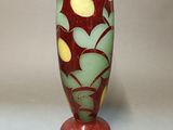 a red vase with a green and yellow design on it