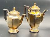 two silver and gold teapots sitting on a table