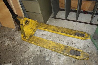 un chariot élévateur jaune posé au sol dans une pièce