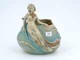 a blue vase with a woman sitting on it