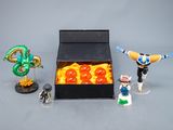 figurines de personnages de Dragon Ball dans une boîte noire posée sur une surface grise