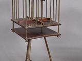 une image représentant une cage à oiseaux posée sur un support, avec deux oiseaux à l'intérieur