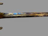 a gold and blue decorated sword on display on a gray background