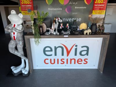a sign that says envia cuisines with a statue of a lizard