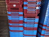 several blue and red plastic crates stacked up in a warehouse