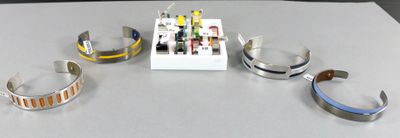 quatre bracelets différents posés sur une table, à côté d'une boîte blanche