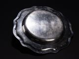 a silver plate on a black surface with a black background
