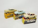 three toy cars are sitting on top of boxes on a white surface