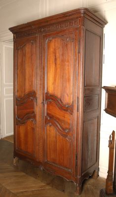 a large wooden armoire in a room with a fireplace