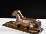 bronze sculpture of a dog laying on a rug on a white surface