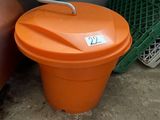 an orange trash can sitting next to a red car