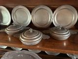 many plates and pans sitting on a wooden shelf