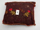 brown pillow with red flowers and a tag on it on a white surface