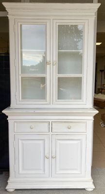 une armoire blanche avec une porte vitrée au milieu d'une pièce