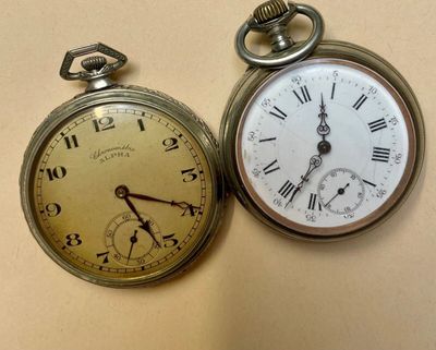 two old pocket watches sitting next to each other on a table