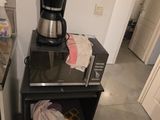 une cafetière posée sur une petite table noire dans une cuisine