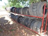 many tires stacked on a red rack under a tree