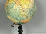 un petit globe terrestre posé sur un socle, sur une table