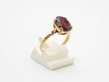 un gros plan d'une bague en or sertie d'une pierre de type grenatite