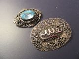 deux broches anciennes en argent et en verre bleu posées sur une surface noire