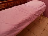 un petit lit recouvert d'un drap rose dans une chambre