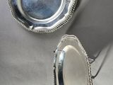 two silver plates with beading on them on a table