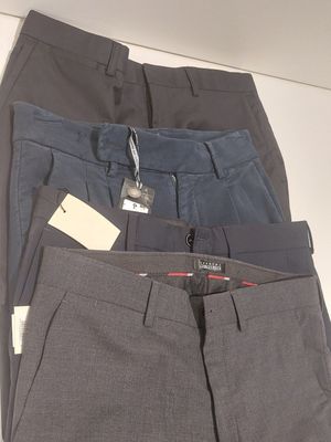 three pairs of men ' s dress pants with tags on them