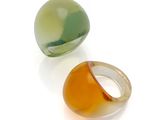 deux anneaux en verre de couleurs différentes posés sur une surface blanche