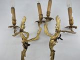 pair of antique brass wall sconces with figurines and candles