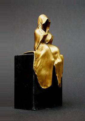 statue d'une femme assise sur un bloc noir, la tête recouverte d'un tissu doré