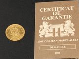 une pièce d'or posée à côté d'une autre pièce d'or sur une surface noire