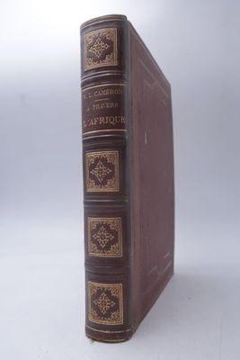 un vieux livre à la couverture marron posé sur une table blanche
