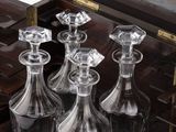 quatre carafes en verre dans un coffret en bois posé sur une table