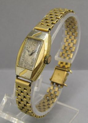 une photo d'une montre-bracelet en or posée sur un socle transparent