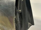 black leather handbag sitting on a wooden stand on a white background