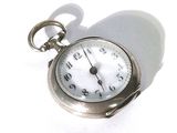 une montre de poche en argent posée sur une surface blanche