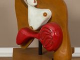 une sculpture représentant une femme assise sur une chaise, un cœur rouge sur les genoux