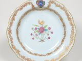 une assiette blanche bordée d'or et décorée de fleurs