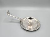 an antique silver plate with a spoon on it on a white surface