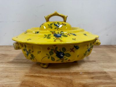 a yellow bowl with flowers on it sitting on a wooden table