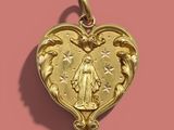 an image of a gold heart shaped pendant on a pink background