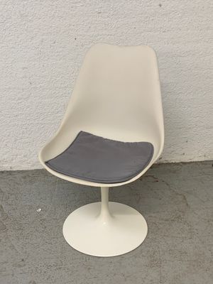 une chaise blanche avec une assise grise posée sur un sol en béton