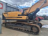 a picture of a yellow and black excavator parked in front of a building