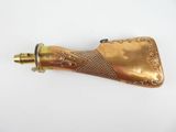 une vieille pipe en laiton avec une poignée en laiton posée sur une surface blanche