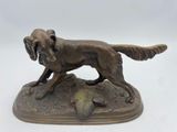 statue représentant un chien assis sur un rocher, un oiseau dans la gueule
